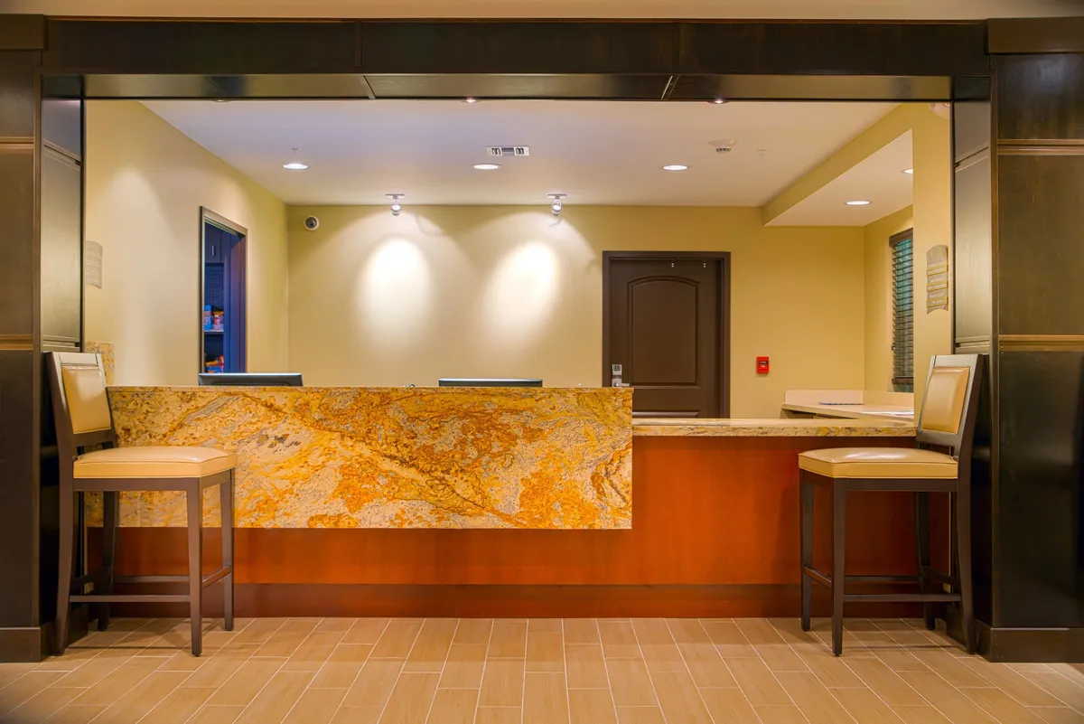 An inviting hotel reception area with a granite countertop, reception desk, and a cozy seating area. The setting is warm and welcoming, with staff ready to assist guests.