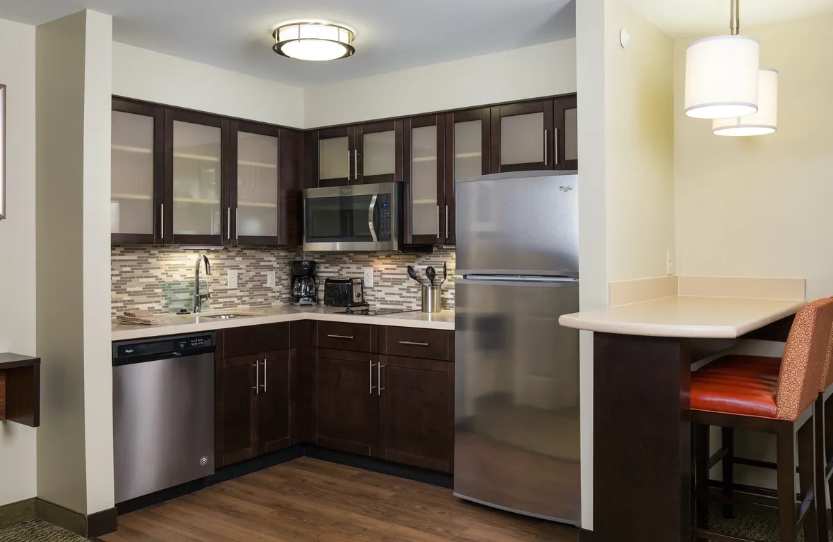 A spacious kitchen area featuring a central island, stainless steel appliances, glass cabinet doors, and a stylish tile backsplash. The setting is ideal for cooking, casual dining, and group gatherings, promoting interaction among guests.